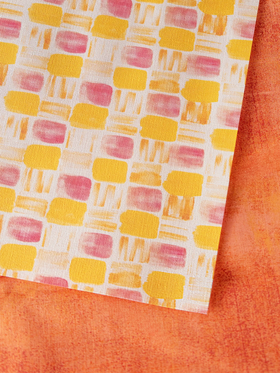 黄色とピンクの四角柄のデザインペーパーを近距離で撮影。紙の質感と柄が詳細に見える。